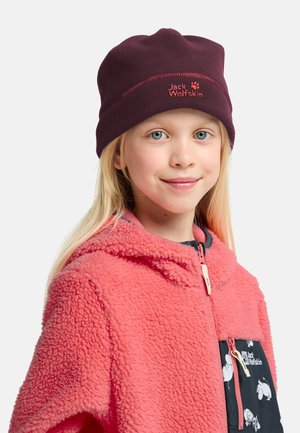 Burgundero Fleece-Mütze mit roter Stickerei. Das Kind trägt eine korallenfarbene Fleecejacke mit einer schwarzen Tasche, die ein weißes Tiermuster aufweist.