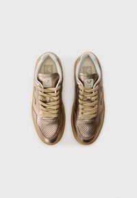 Sneakers metallici color bronzo con dettagli perforati, lacci beige e suole in gomma. Presentano un rivestimento comodo e un'etichetta con logo sulla linguetta.