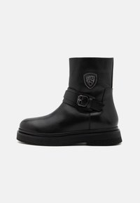 Mustat nahka nilkkurit, joissa on pyöreä kärki, tukeva pohja, leveä hihna soljella ja koristeellinen kilpimerkki sivussa.