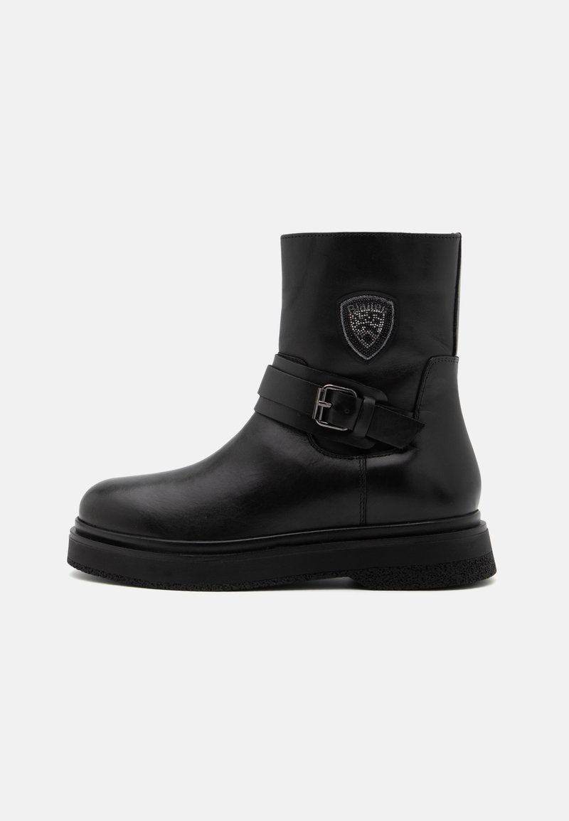 Mustat nahka nilkkurit, joissa on pyöreä kärki, tukeva pohja, leveä hihna soljella ja koristeellinen kilpimerkki sivussa.