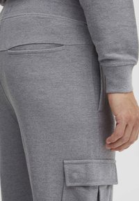 Gray sweatpants with textured fabric, featuring a side pocket and elastic cuffs. The design includes a fitted waistband for comfort.