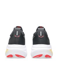 Baskets de sport noires avec une tige texturée, une semelle intermédiaire blanche, des accents rouges contrastants sur la semelle extérieure et une languette au talon.