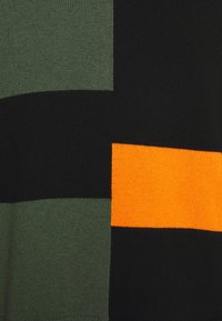 Suéter de punto con un diseño de bloques de color en secciones de verde oliva, negro y naranja brillante. Textura suave con un acabado blando.