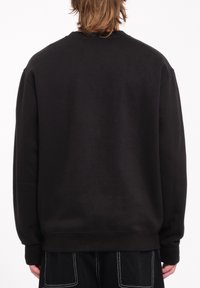 Sudadera negra con un corte relajado, puños y dobladillo acanalados, textura suave y sin logotipos ni patrones visibles, vista desde la parte de atrás.