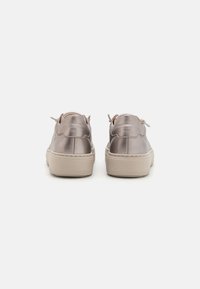 Metallisch taupefarbene Sneakers mit glatter Oberfläche, runden Schnürsenkeln, einem erhöhten Absatz und kontrastierenden, hellbeigen Gummisohlen.