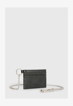 Tarjetero de piel negra con cuatro compartimentos para tarjetas y una cadena. Presenta un anillo de metal y un clip de mosquetón para su sujeción. Textura lisa.