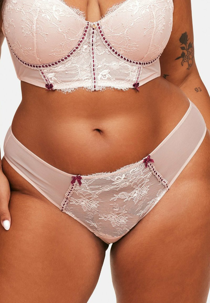 Ensemble de lingerie en dentelle et mesh rose doux avec des accents bordeaux. Le soutien-gorge présente de la dentelle florale, un soutien-gorge à armatures et des nœuds décoratifs sur les culottes.