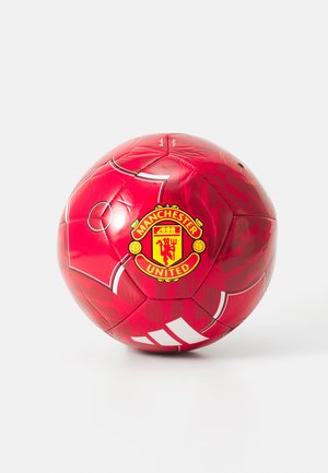Red soccer ball featuring the Manchester United logo, with a glossy surface and white striped accents. Distinctive pentagonal and hexagonal panels.