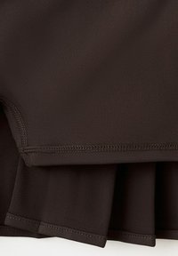 Primer plano de capas de tela marrón oscuro con costuras visibles y bordes doblados, destacando la textura y los detalles de las costuras.