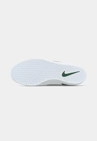 Talpa de adidași Nike din cauciuc alb cu un model texturat și un logo verde Nike pe călcâi. Margini netede, concepută pentru aderență.