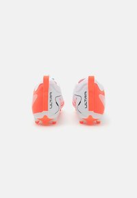 Botas de fútbol blancas y rosas brillantes con una superficie texturizada, prominente marca "ULTRA" en el costado y distintivos acentos naranjas en el talón.