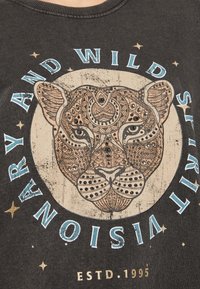 Černé bavlněné tričko s podrobnou grafikou leopardu s metalickými akcenty, obklopené textem v modré a zlaté barvě. Klasický kulatý výstřih.