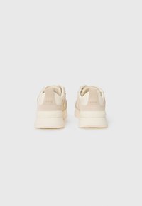 Beiga sneakers med en slät yta, som har en dämpad sula, subtil logotyp på hälen och en elegant, modern silhuett.