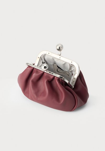 Petit porte-monnaie en cuir bordeaux ouvert avec cadre et fermoir en métal argenté, montrant un intérieur en tissu rayé et une étiquette cousue à l'intérieur.