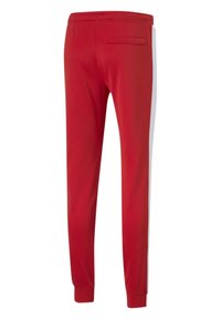 Red athletic pants with a relaxed fit, elastic waistband, one back pocket, and white side panels, made of soft, breathable fabric.
