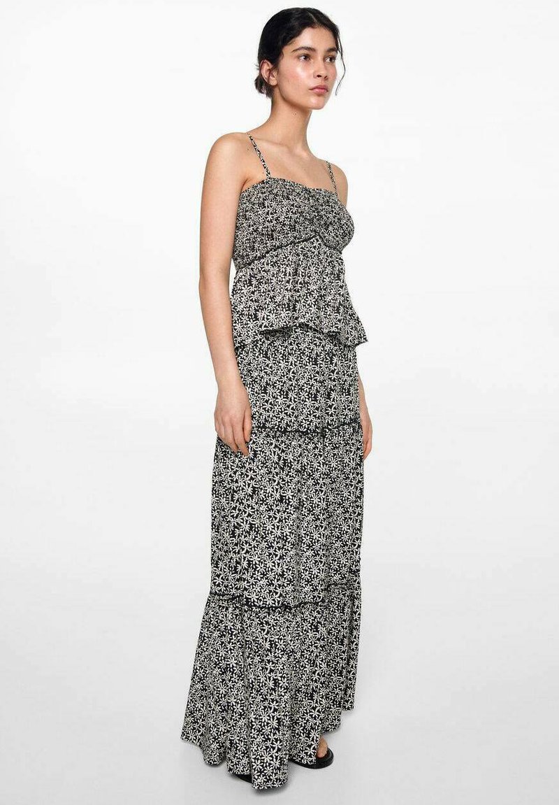 Maxiklänning med svart och vit blommönster, spagettiband, volangsteg och en svängd nederkant. Lätt tyg med mjuk textur.