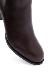Brown leather ankle boot with a sleek, smooth texture and rounded toe. Features a low block heel and a minimalistic design.