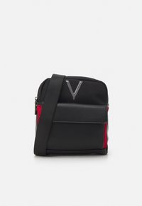 Borsa a tracolla nera con dettagli rossi, realizzata in tessuto testurizzato e pelle liscia. Presenta un logo argentato e una tracolla regolabile.