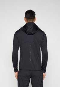 Czarna sportowa kurtka z kapturem, o gładkiej fakturze, z długimi rękawami i pionowym logo na plecach.