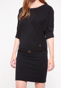 Tmavě šedé pletené šaty s krátkými rukávy, přiléhavý střih a hnědý opasek s přezkou ve tvaru kruhu v pase. Hladká textura, minimální zdobení.