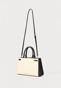 Schwarze und cremefarbene Handtasche mit einer strukturierten Form, strukturierten Oberfläche, zwei oberen Griffen und einem abnehmbaren Schultergurt mit goldenen Hardware-Akzenten.