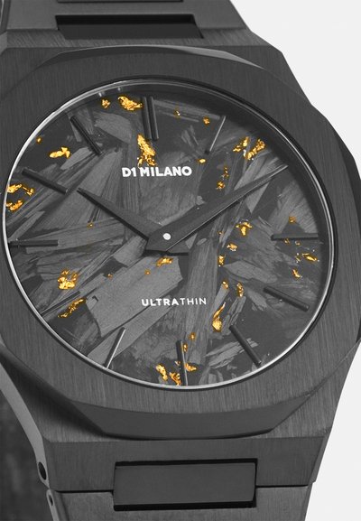 Μαύρο οκταγωνικό ρολόι με υφασμάτινο γκρι καντράν, χρυσές λεπτομέρειες και μαύρους δείκτες ωρών. Διαθέτει μινιμαλιστικό σχεδιασμό και λεπτό προφίλ.