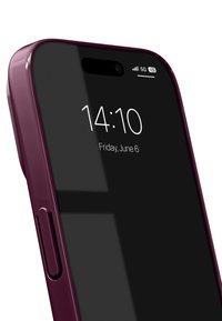 Älypuhelin kiiltävällä, syvän violetilla suojakuorella, musta näyttö, kellonaika 14:10, päivämäärä 6. kesäkuuta, 5G-signaalikuvake kulmassa.