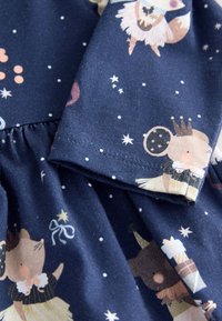 Dunkelblauer Stoff mit verspielten Tiermustern in sanften Farben, verziert mit Stern- und Kreisakzenten; enthält eine geraffte Naht.