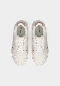 Ζευγάρι λευκών αθλητικών παπουτσιών με ροζ λεπτομέρειες και λευκά κορδόνια, με το όνομα της μάρκας "Anna Field" ορατό στις εσωτερικές σόλες, εμφανιζόμενο από πάνω.