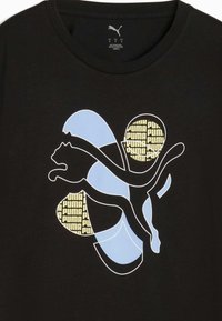 Musta t-paita, jossa on suuri sininen ja keltainen graafinen kuvasto, esittäen tyyliteltyä kissaa ja pyöreitä elementtejä, joissa on "PUMA"-tekstit.