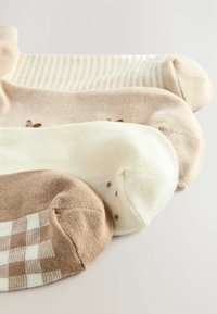 Three pairs of socks featuring various shades of beige and cream. Designs include stripes, dots, and a checkered pattern. Soft texture.