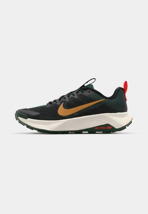 Černé a zelené sportovní boty s texturovaným svrškem, zlatým Nike swoosh, červeným akcentem na patě a silnou bílou mezipodešví.
