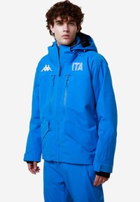 Giacca impermeabile blu con cappuccio, zip frontale, due tasche sul petto e logo "ITA" ricamato; presenta dettagli neri sui polsini.