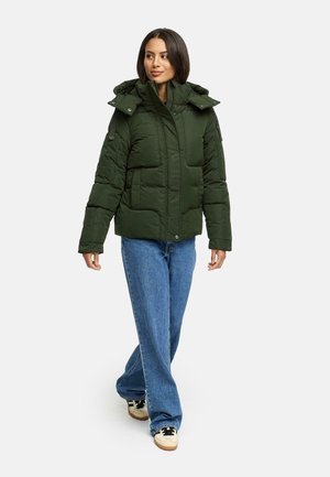 Donkergroen pufferjack met een ritssluiting aan de voorkant, meerdere zakken, een afneembare capuchon en verstelbare banden op de schouders, gedragen met lichtblauwe jeans.