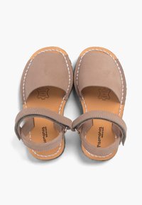 Ruske nahkane sandale z odprtimi prsti, bež trakovi in belim šivom. Imajo zavarovan gleženjski trak in rjav notranji del s logotipom.