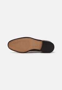 Semelle de chaussure en cuir brun avec une surface lisse et un motif strié ; présente un talon noir et des détails cousus autour des bords.