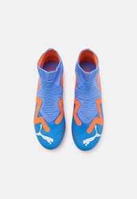 Blauwe en oranje sport schoenen met een gestructureerde bovenkant, sokachtige pasvorm en geperforeerd ontwerp. Voorzien van een wit logo aan de zijkant.