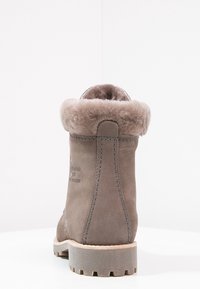 Botte en suède gris avec un revers en fausse fourrure et une semelle en caoutchouc texturé. Présente des détails de couture et un logo sur le côté.