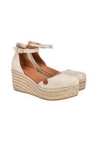 Sandalias de cuña de ante beige con tiras tobilleras, que presentan una suela de yute trenzado y un acento de cuero marrón en el lateral. Textura suave y punta redondeada.