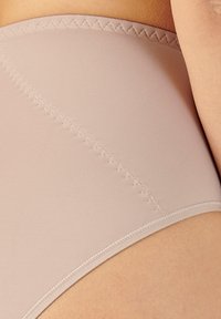 Mutande beige a vita alta realizzate in un tessuto liscio con una cucitura a zigzag testurizzata lungo l'elastico in vita e le aperture delle gambe.