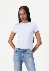 Svijetloplava majica kratkih rukava od mekanog pamučnog materijala s okruglim izrezom, u kombinaciji s svijetloplavim trapericama s pet džepova.