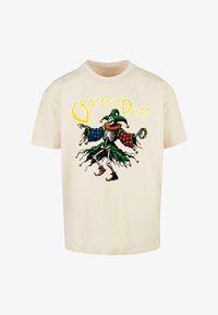 Camiseta de manga corta color crema con un gráfico colorido de un bufón esquelético, patrones de tablero de ajedrez y el texto "Grateful Dead" arriba.