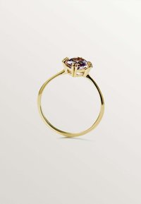 Anillo de oro con una gran piedra preciosa ovalada de color púrpura engastada en una montura de garras, con una banda delgada y suave.