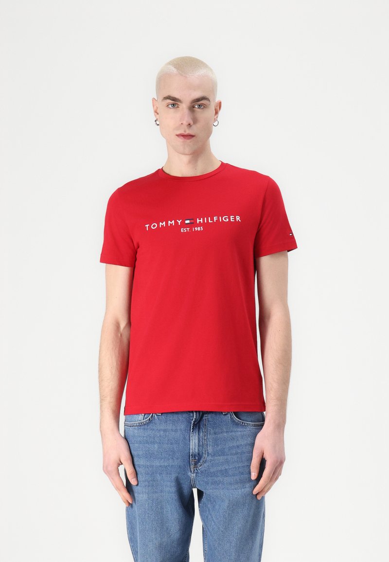 Camiseta de algodón roja con cuello redondo, mangas cortas y logo impreso "TOMMY HILFIGER EST. 1985" en el centro frontal.