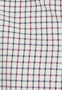 Tessuto di cotone con uno sfondo bianco caratterizzato da un motivo a scacchi composto da quadrati rossi e blu navy, uniformemente distribuiti e con una texture.