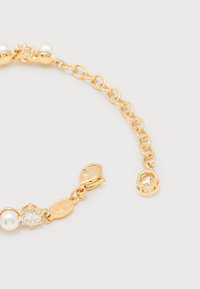 Χρυσό βραχιόλι αλυσίδα με λευκές πέρλες, διαυγή πολύτιμους λίθους και κούμπωμα αστακού σε λευκό φόντο.