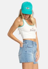White cropped tank top with turquoise trim and "Billabong" logo, paired with light blue denim shorts featuring front and back pockets.