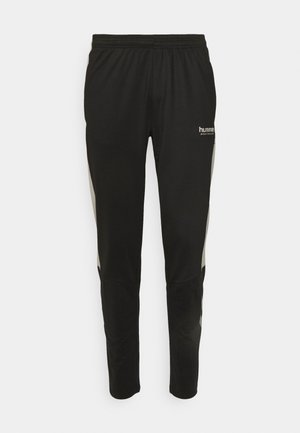 Zwarte sportbroek met een elastische tailleband, subtiele accenten aan de zijkant en een logo op de linkerdij in een reflecterende afwerking.