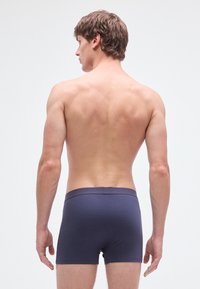 Boxer de algodón elástico azul marino con una cinturilla elástica suave, diseño ajustado y aspecto minimalista, mostrado desde una vista trasera.