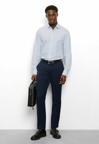 Hellblau gemustertes Hemd mit Knöpfen, marineblaue, maßgeschneiderte Hose, schwarzer Gürtel und schwarze Schuhe; hält eine schwarze Aktentasche; glatte Textur.